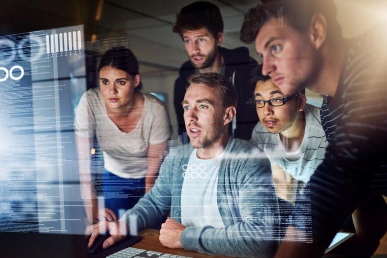 Image of individuals crowed around a computer screen.